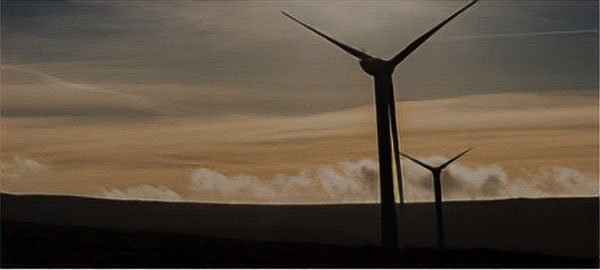 Lone wind turbine set against a sunny sky with rolling clouds