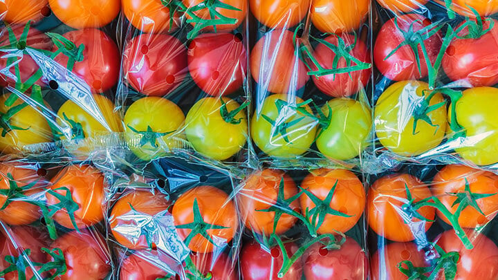 Rows of red, yellow, and orange tomatoes packaged in cellophane