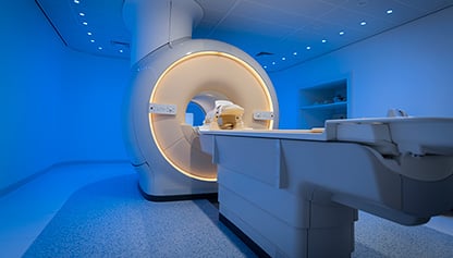 An open air MRI scanner machine in a room with blue walls.