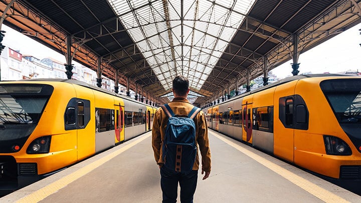 Man standing on a train platform between two modern yellow trains