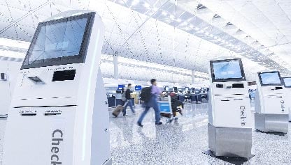 Man rushing through airport with luggage, check-in consoles in view.