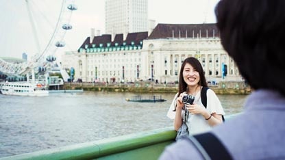 Woman smiling and positing for a photo on a bridge with the London Eye in the background