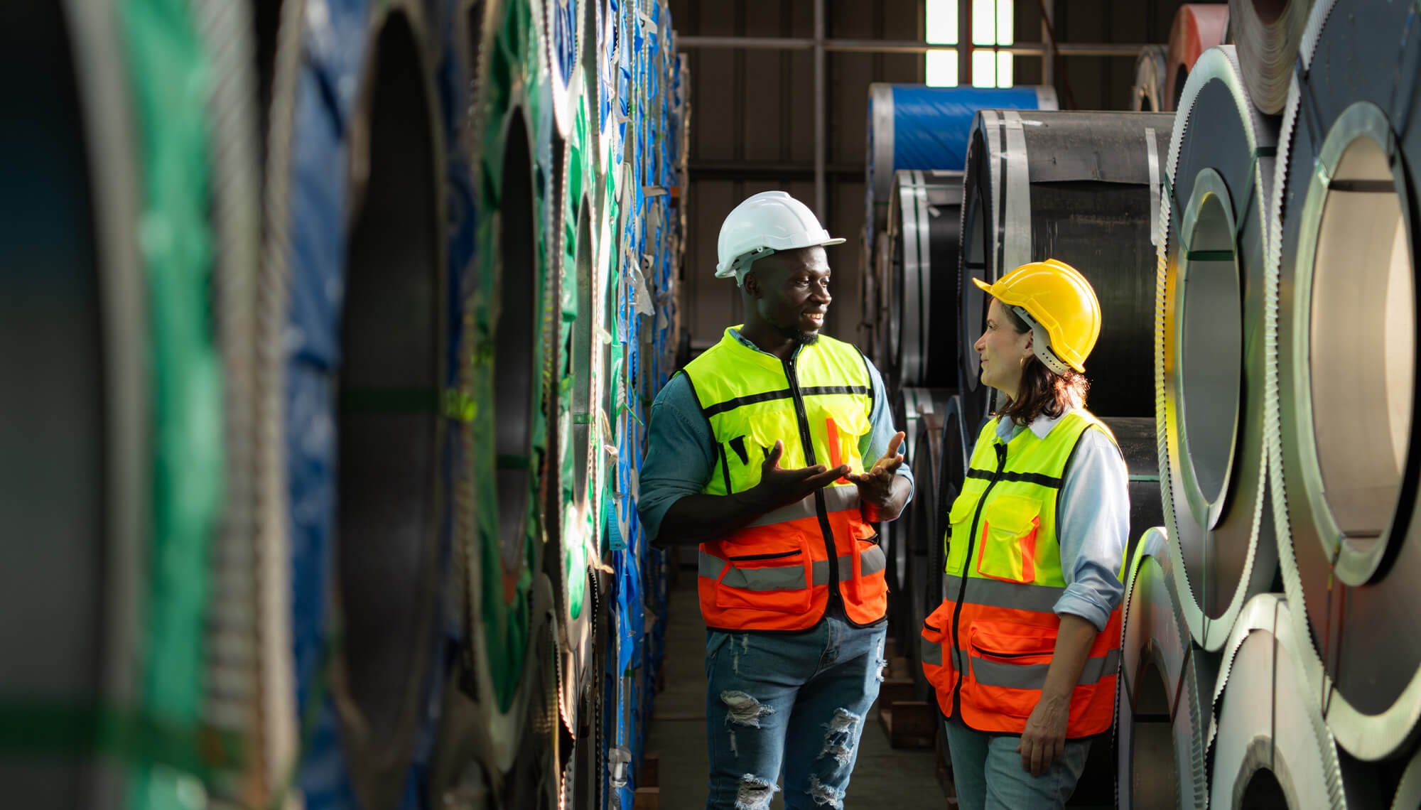 Workers conversing near rolls of sheet metal