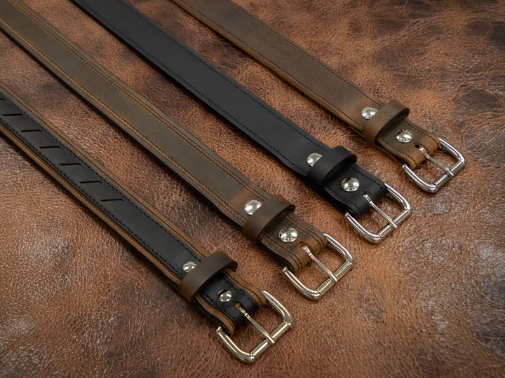 Four leather belts of various design on a leather backdrop