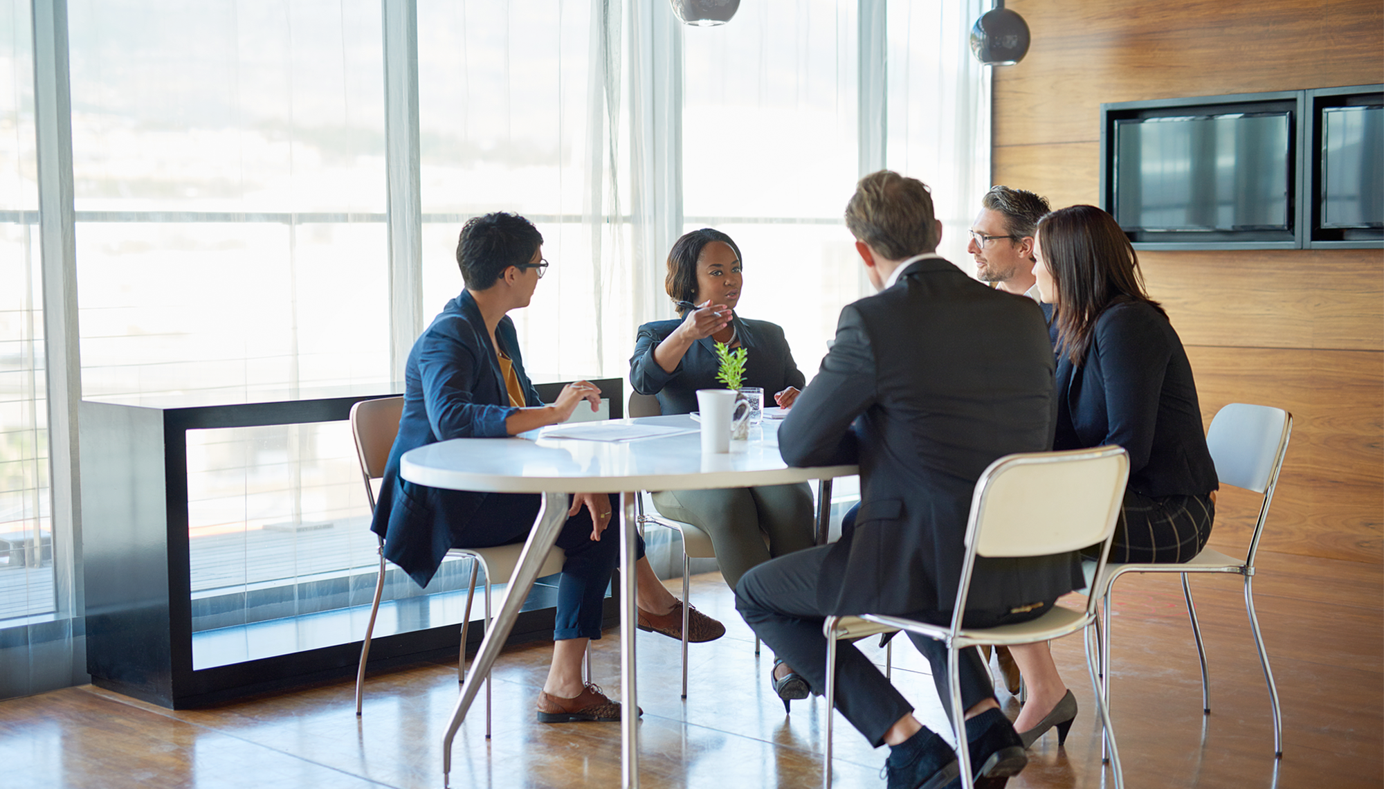 Five professionals sitting around a conference table in discussion