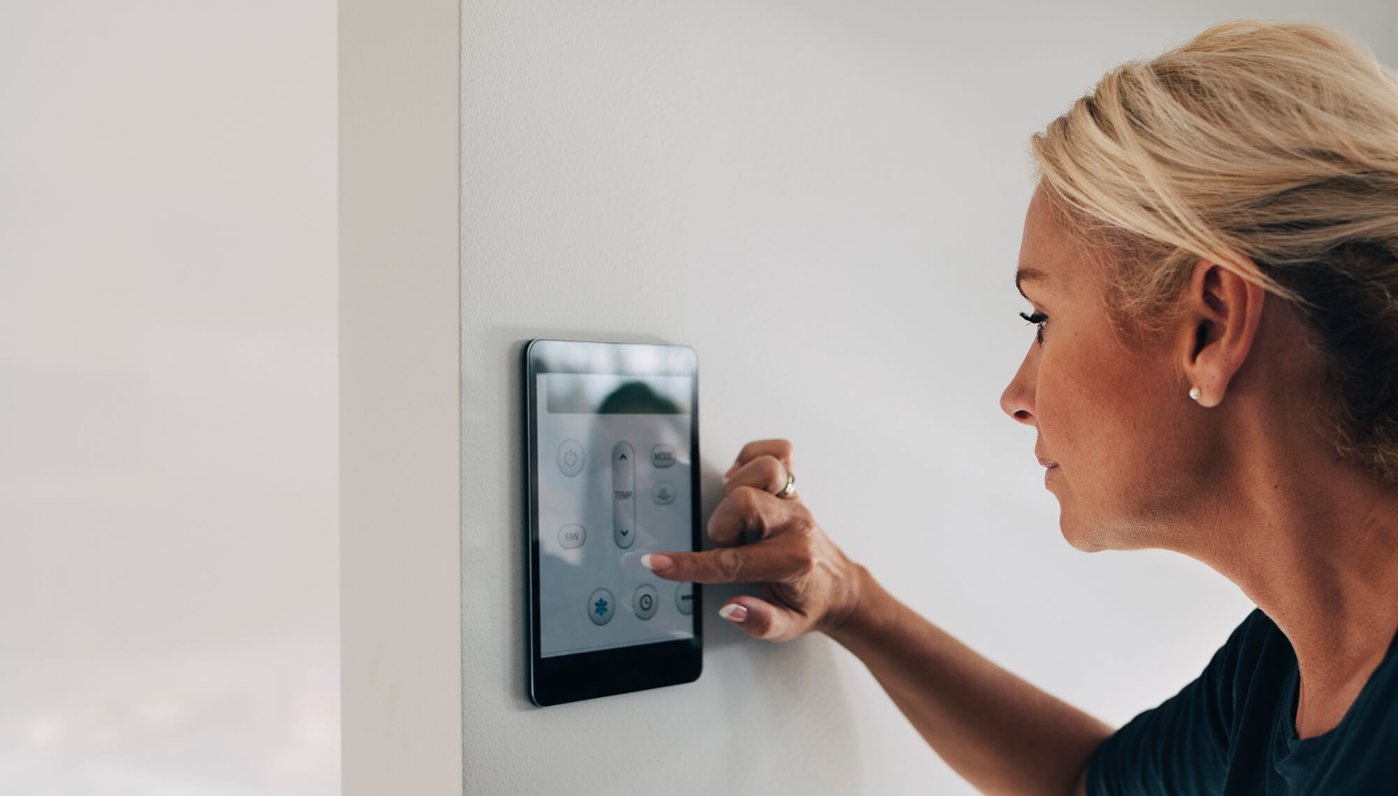 Woman touching a smart thermostat