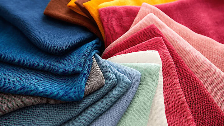 A collection of textured and folded fabrics arranged by color
