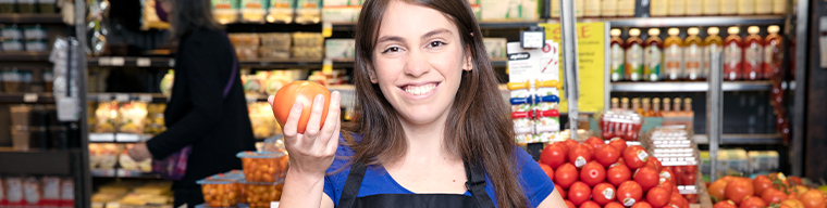 Woman smiling holding a tomato