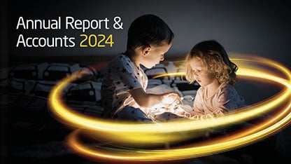 2025 Annual Report cover showing two young children in a dark room holding string lights with a glowing yellow light around them