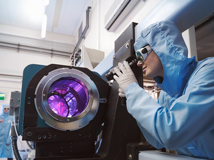 Scientists in protective clothing and goggles in laboratory next to laser equipment