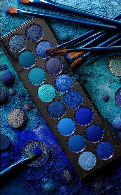A variety of shades of blue eye shadow and make up brushes