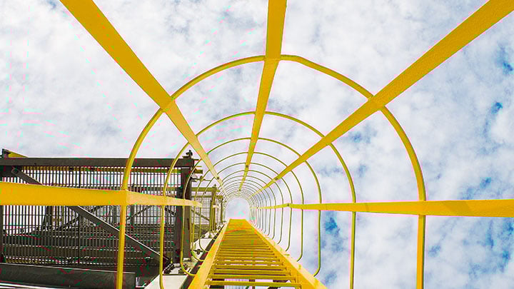 Looking up inside a metal yellow ladder in protective scaffolding