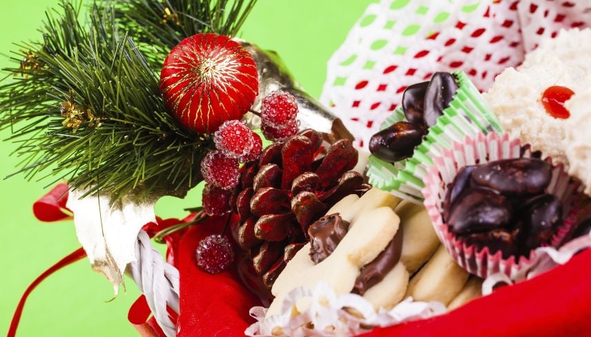A basket filled with assorted Christmas cookies and treats, set against a vibrant green background.