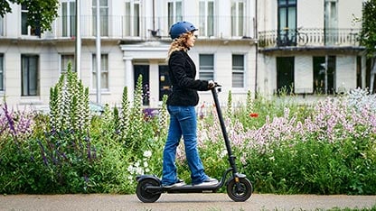 Woman riding an electric scooter with protective headgear